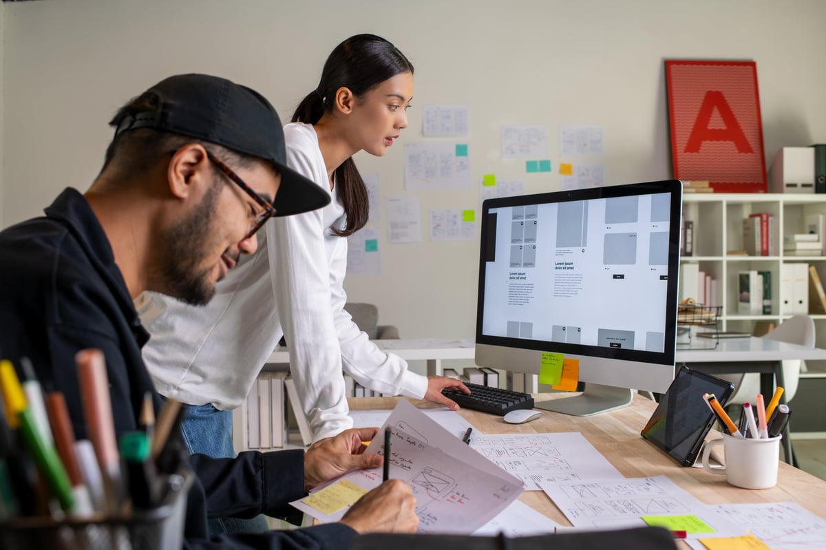 UX UI designers discussing and brainstorming on wireframes for a website and mobile app prototype